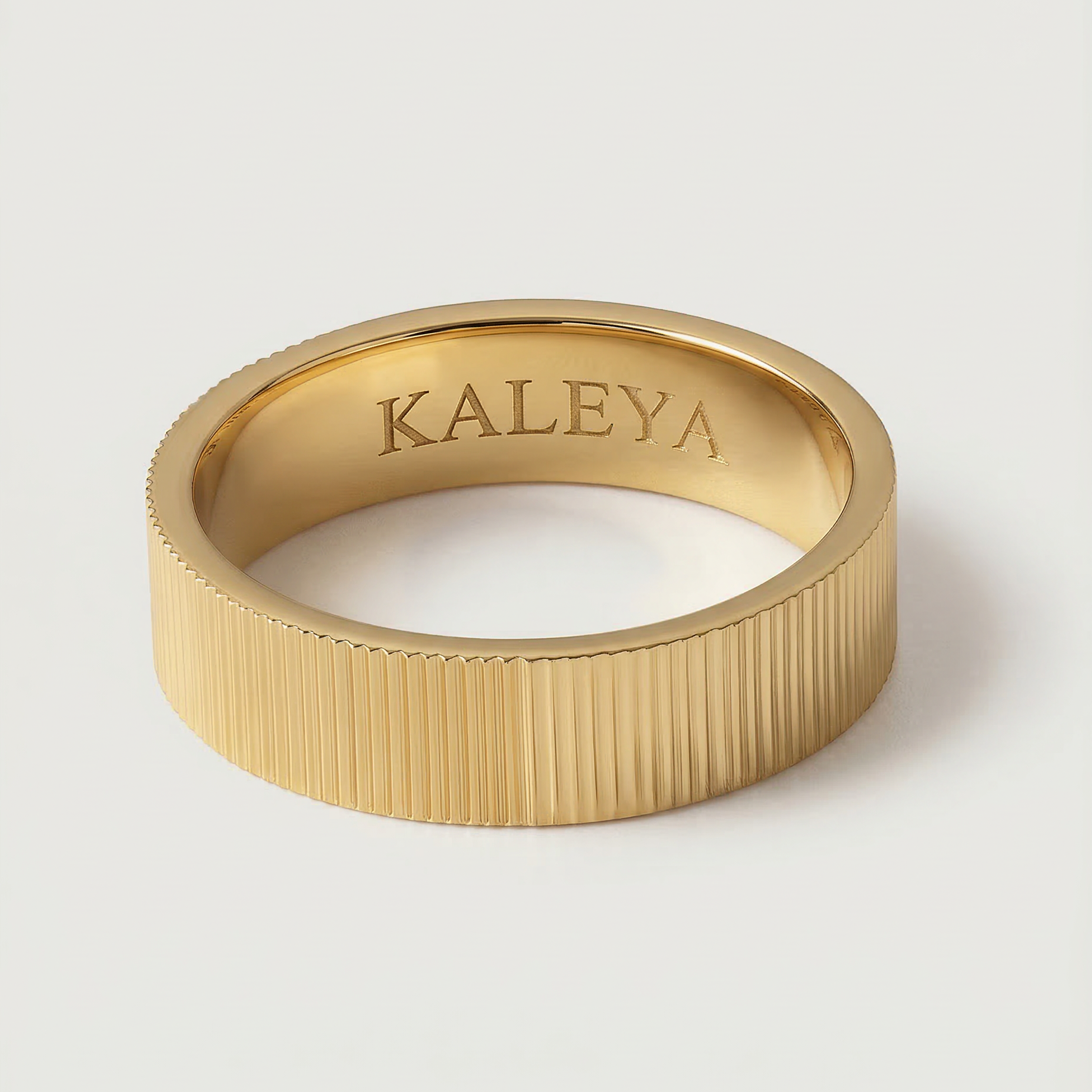 A gold plated band ring with a ribbed texture, displayed on a white background.