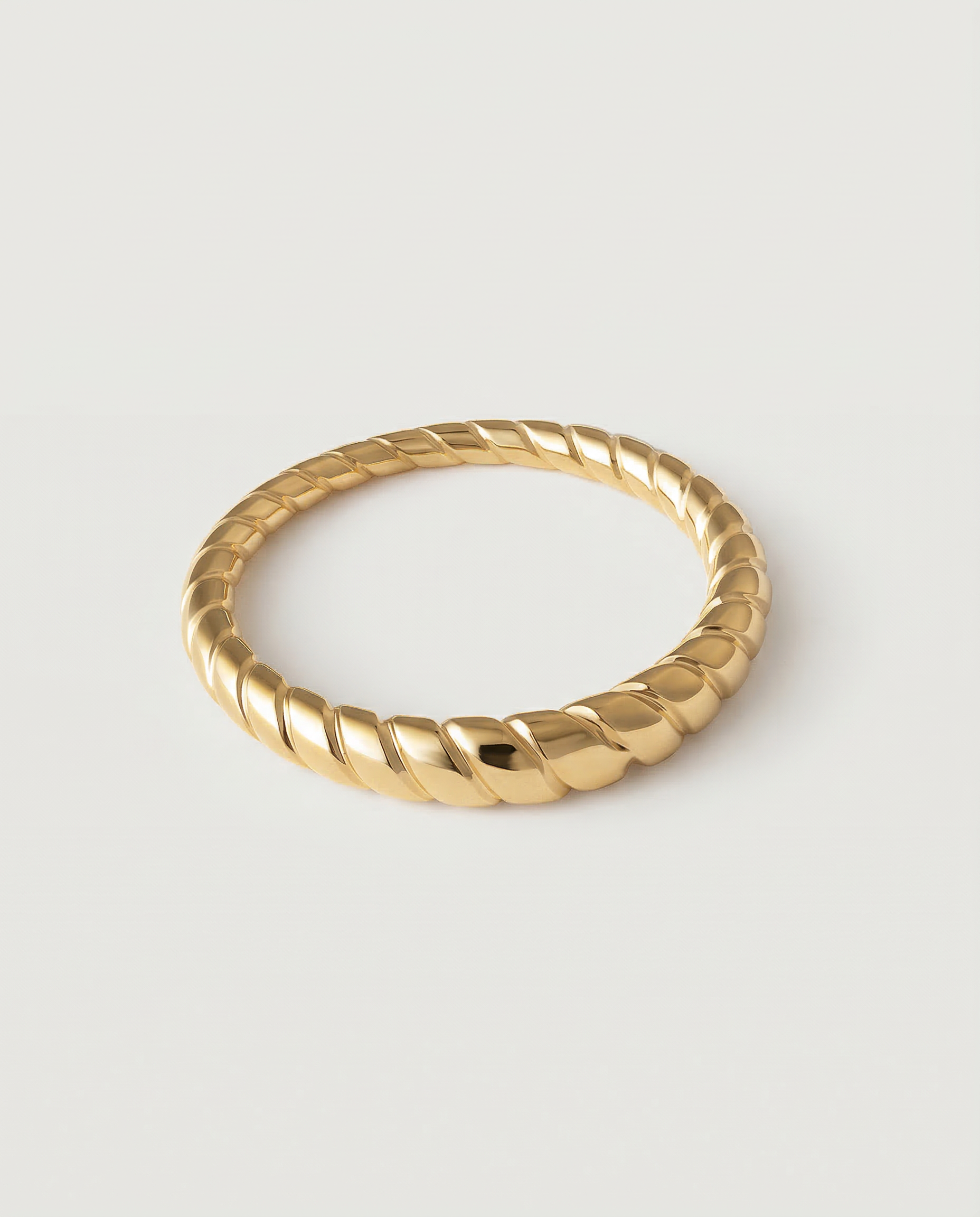 A gold-plated metal ring with a twisted rope design, displayed against a white background.