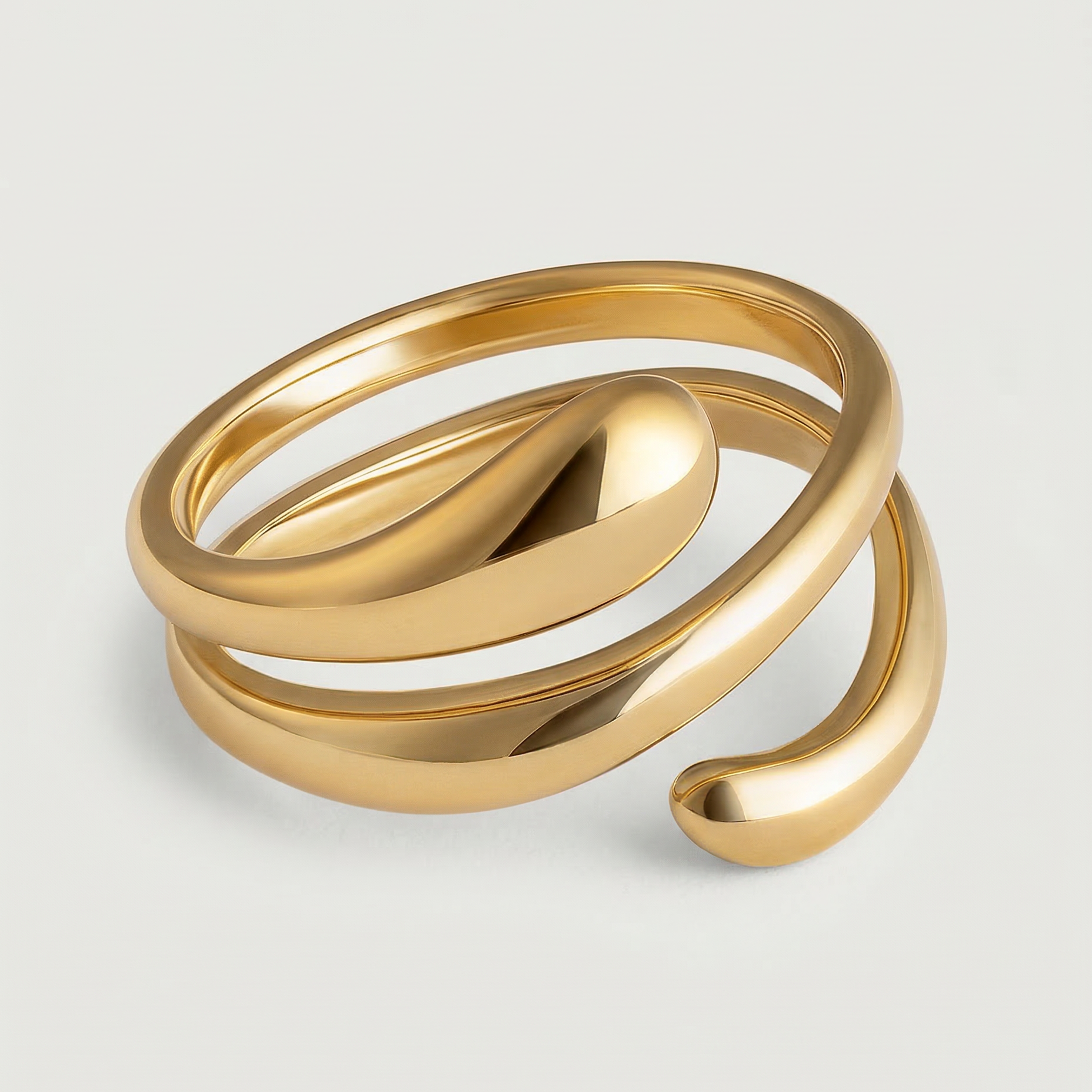 A gold-plated stainless steel ring with an architectural, coiled design, displayed against a white background.