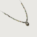 A necklace with variegated African turquoise beads and silver spacers, ending in a teardrop-shaped pendant.