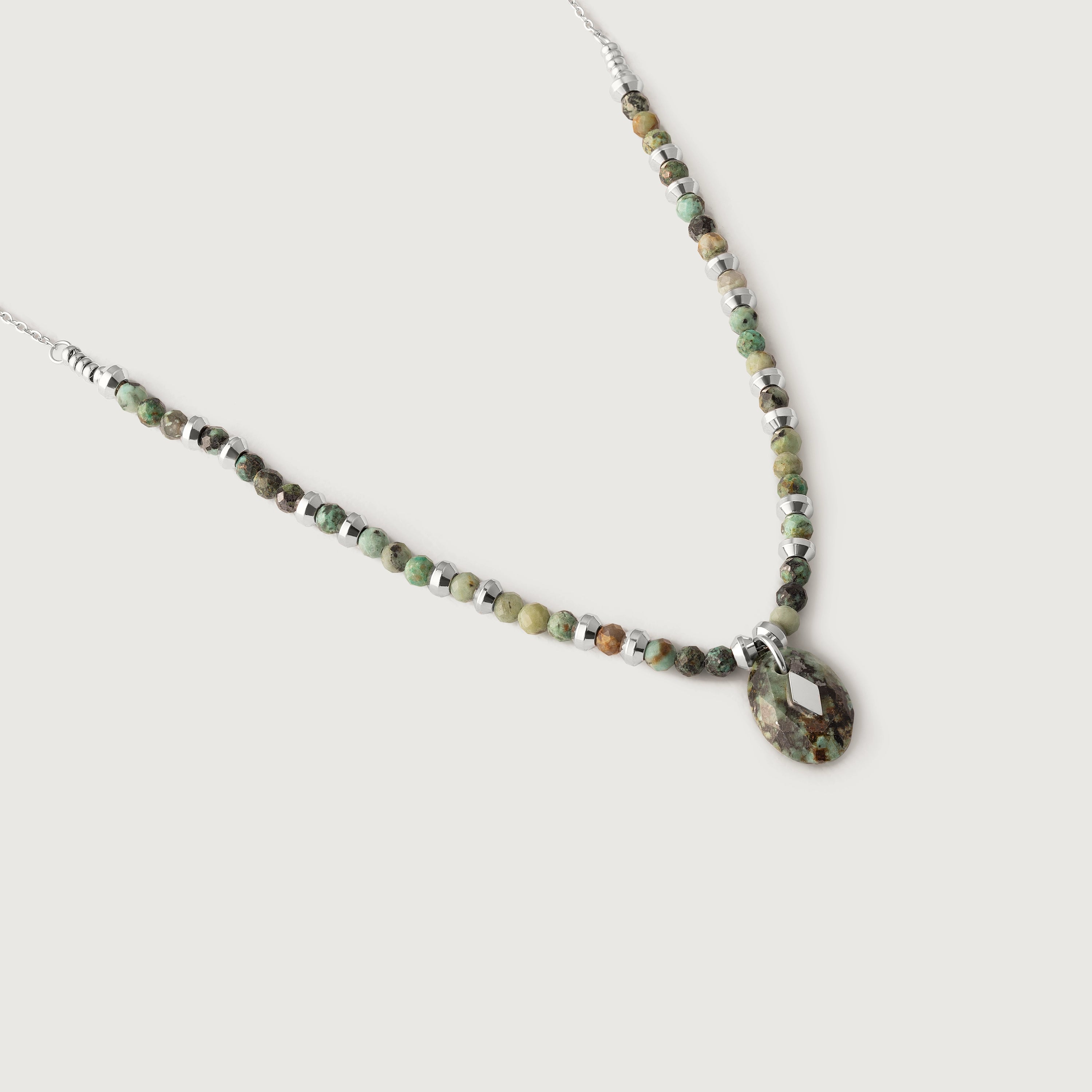 A necklace with variegated African turquoise beads and silver spacers, ending in a teardrop-shaped pendant.