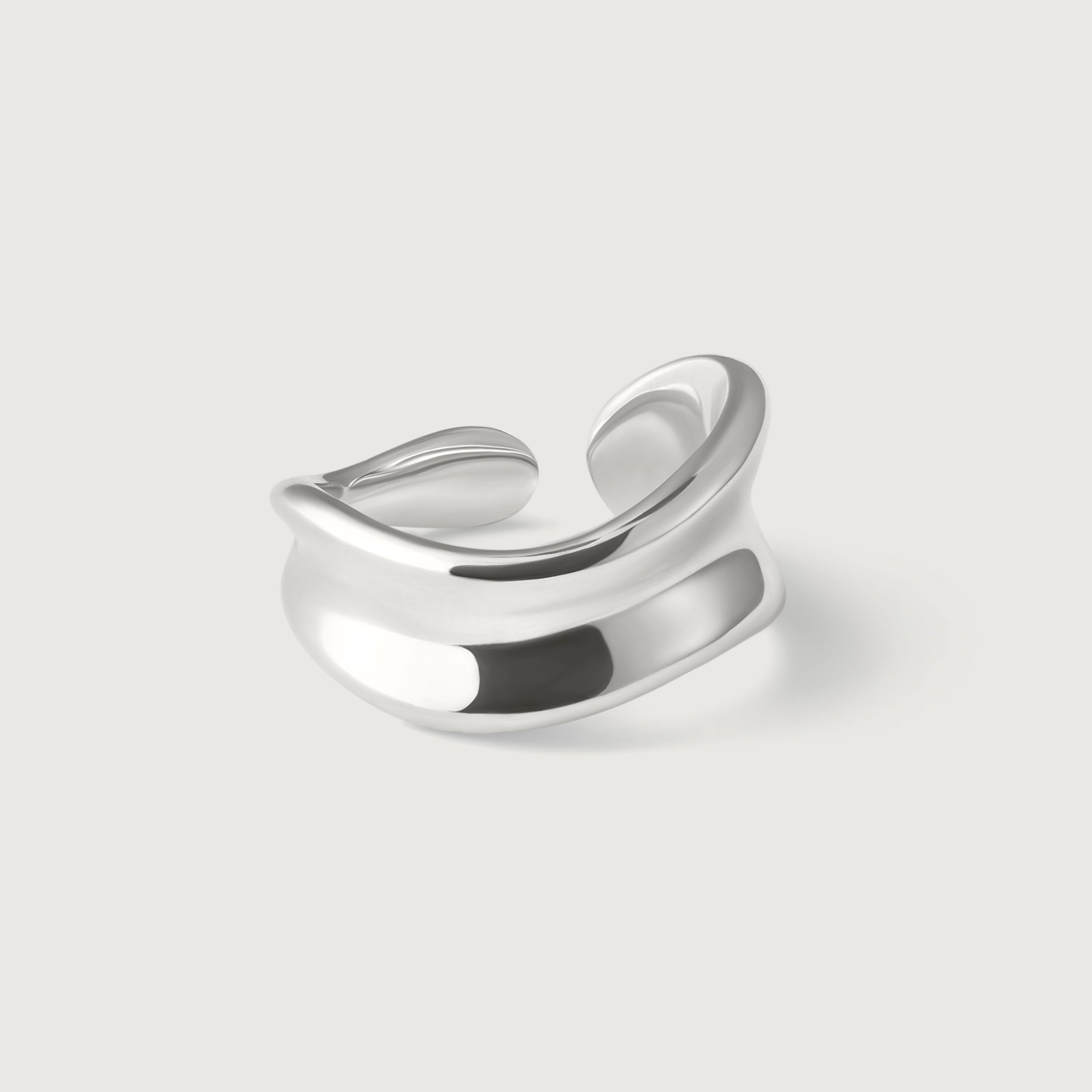 A sterling silver, asymmetrical, open-ended ring with a smooth, polished surface.