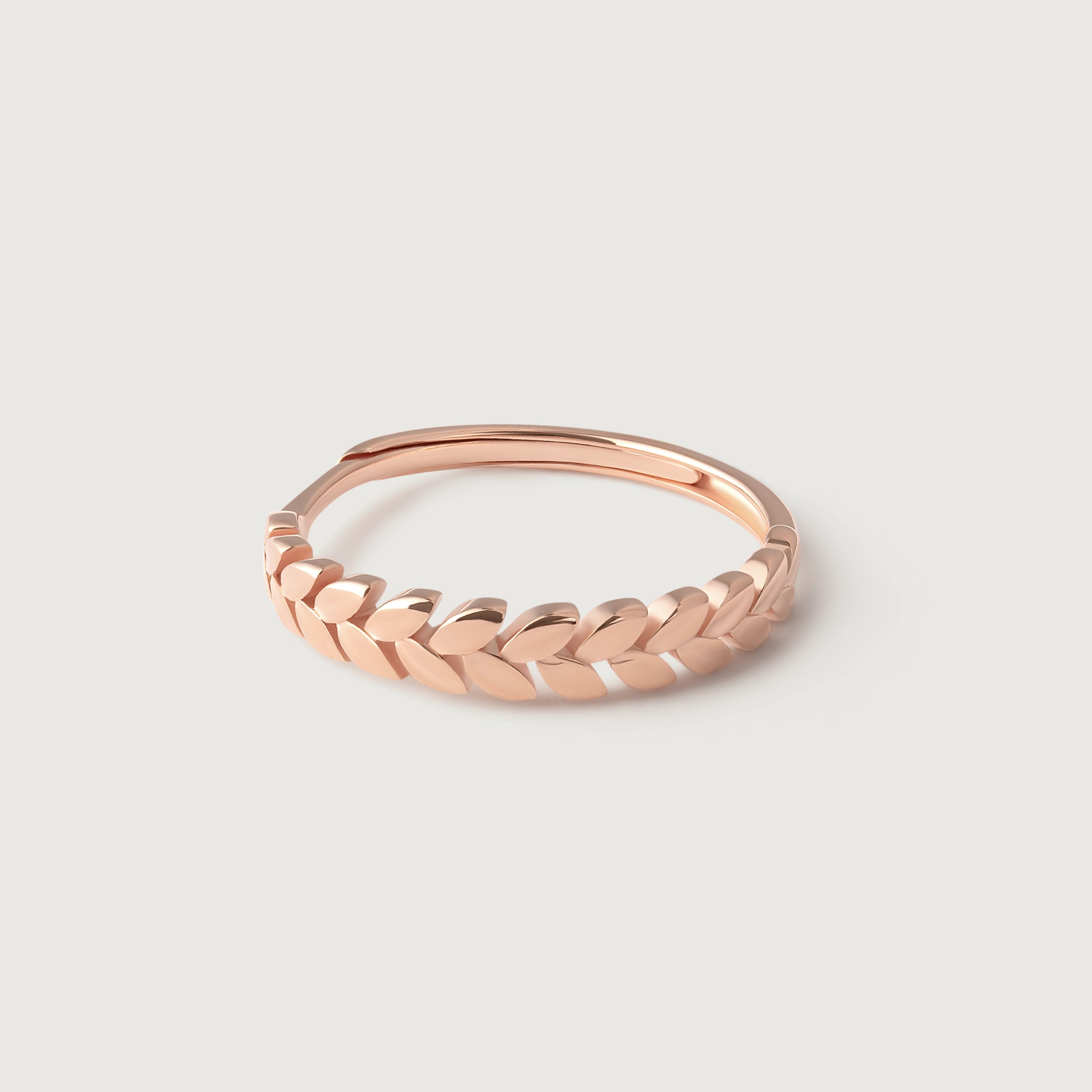 A rose gold ring with a band designed from intertwined leaves, symbolizing victory and honor.