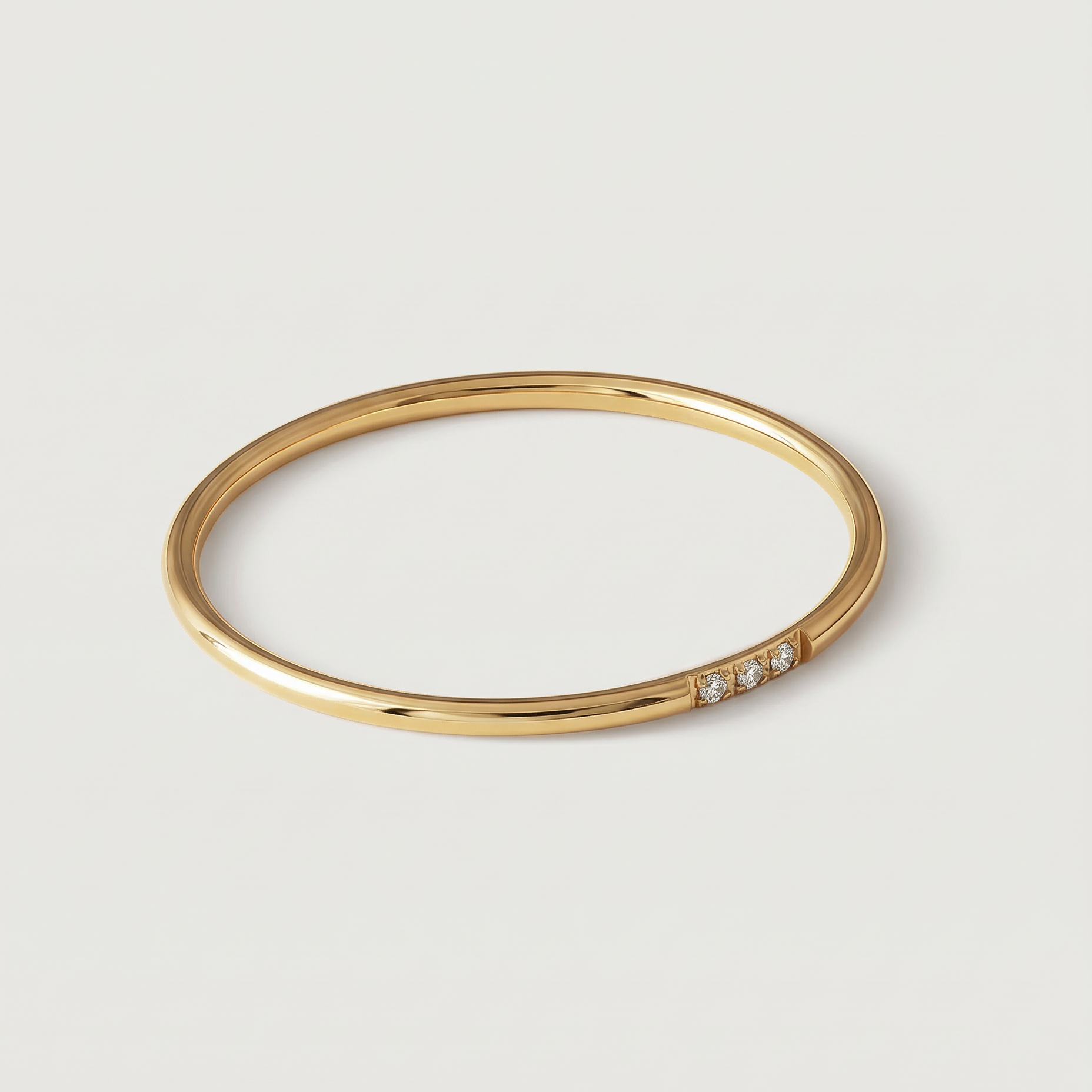 A gold-plated ring with a polished surface and a trio of brilliant cut cubic zirconia stones on one side, displayed against a white background.